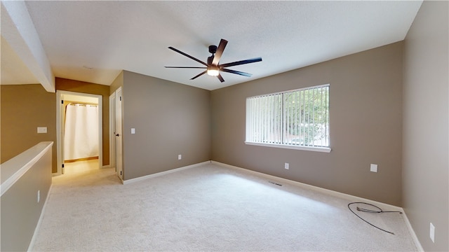 spare room with light carpet, ceiling fan, and a textured ceiling