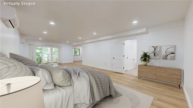 bedroom featuring light hardwood / wood-style flooring and a wall unit AC