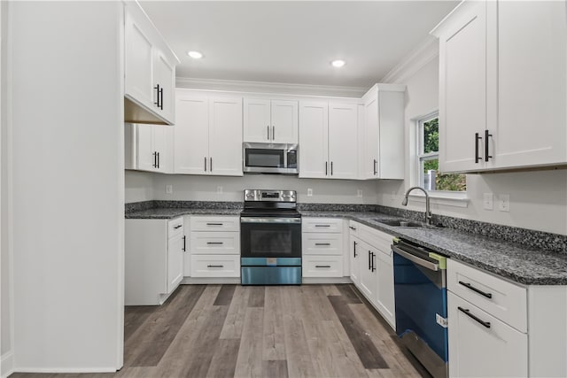 kitchen featuring hardwood / wood-style flooring, white cabinets, crown molding, sink, and appliances with stainless steel finishes