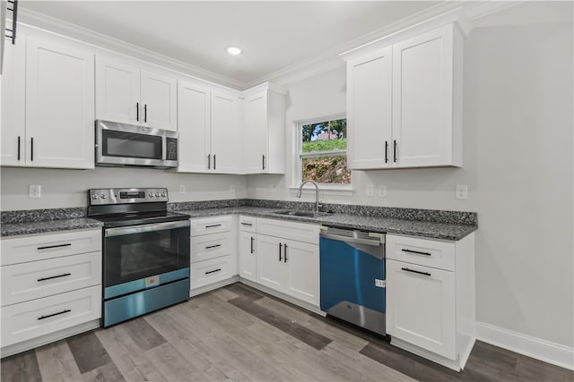 kitchen featuring crown molding, white cabinets, stainless steel appliances, hardwood / wood-style flooring, and sink