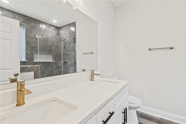 bathroom featuring an enclosed shower, hardwood / wood-style flooring, toilet, and dual bowl vanity