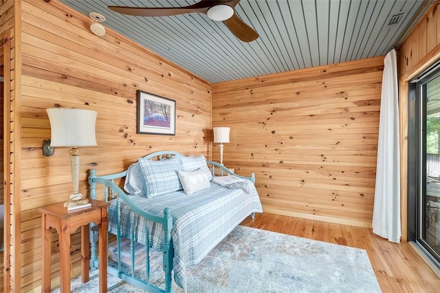 bedroom with wooden walls, ceiling fan, and light hardwood / wood-style flooring