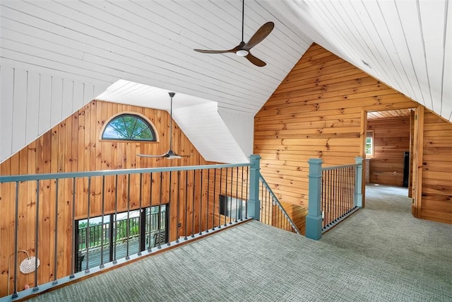 additional living space with ceiling fan, high vaulted ceiling, carpet floors, and wood walls