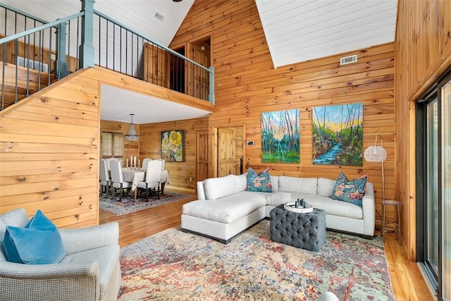 living room with hardwood / wood-style flooring, high vaulted ceiling, and wood walls