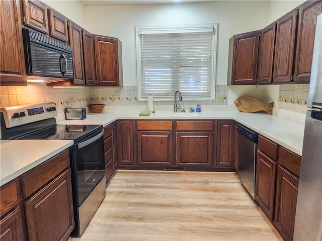 kitchen with light wood-type flooring, stainless steel appliances, and sink