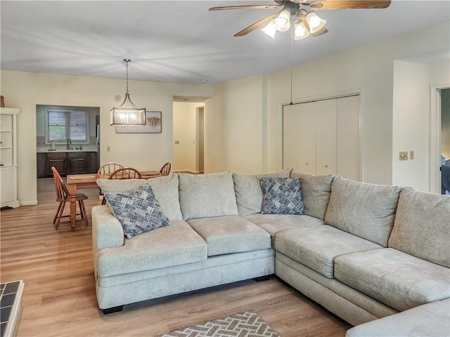 living room with hardwood / wood-style flooring, ceiling fan with notable chandelier, and sink