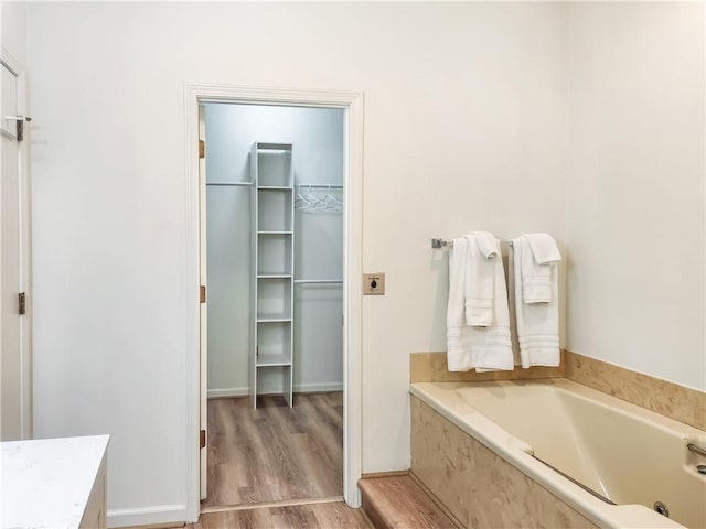 bathroom with hardwood / wood-style floors, vanity, and tiled tub