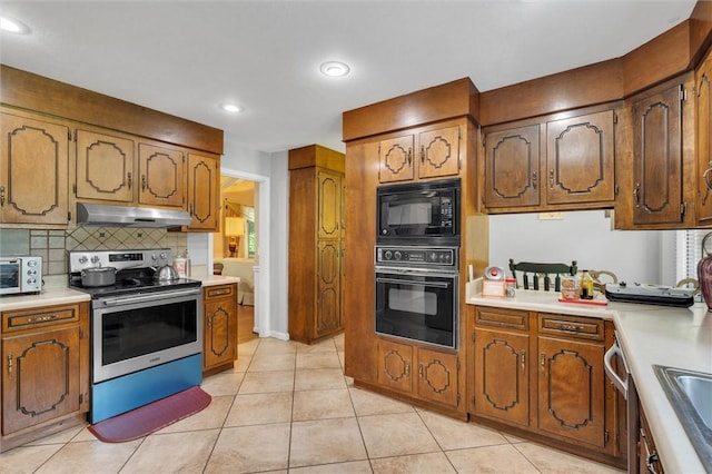 kitchen featuring sink, backsplash, light tile patterned floors, and black appliances