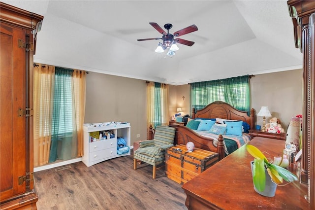 bedroom with ceiling fan, dark wood-type flooring, and a tray ceiling