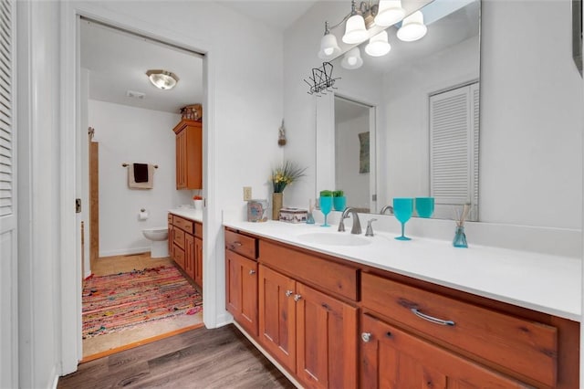 bathroom featuring toilet, vanity, a notable chandelier, and hardwood / wood-style flooring