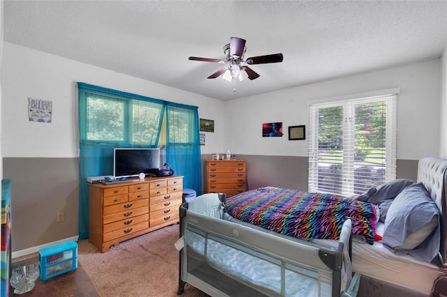 carpeted bedroom featuring ceiling fan and a textured ceiling