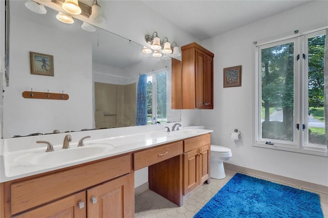 bathroom featuring toilet, vanity, tile patterned flooring, and a healthy amount of sunlight