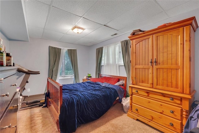 bedroom with carpet floors and a drop ceiling