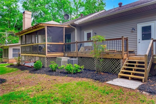 rear view of house with a deck, a sunroom, and central AC unit