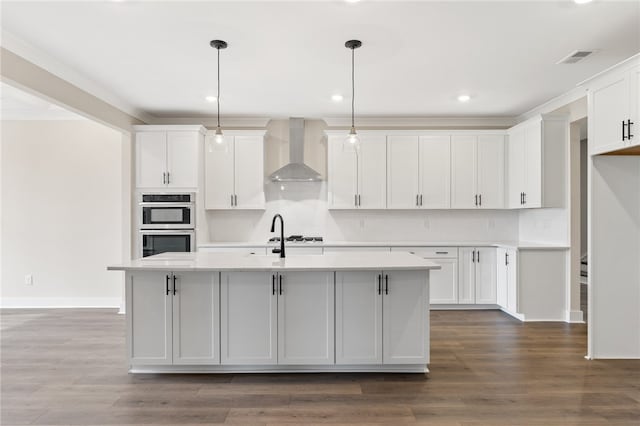 kitchen with white cabinetry, wood-type flooring, pendant lighting, and wall chimney exhaust hood