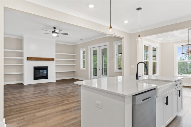 kitchen featuring decorative light fixtures, dishwasher, hardwood / wood-style floors, and a kitchen island with sink