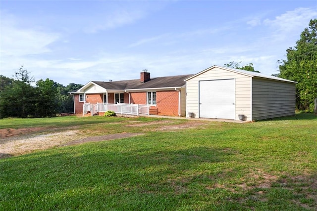 view of front facade featuring a porch, a garage, an outbuilding, and a front lawn