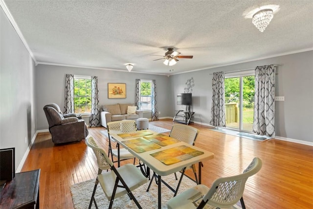 dining space with crown molding, ceiling fan, a healthy amount of sunlight, and hardwood / wood-style flooring