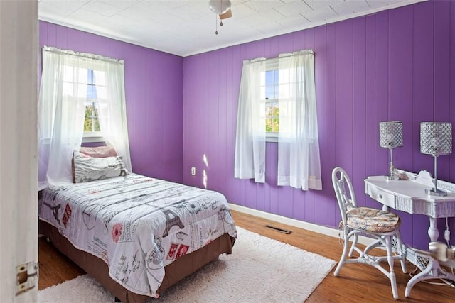 bedroom with multiple windows, ceiling fan, and hardwood / wood-style flooring