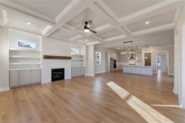 unfurnished living room featuring ceiling fan, a fireplace, light hardwood / wood-style flooring, and coffered ceiling