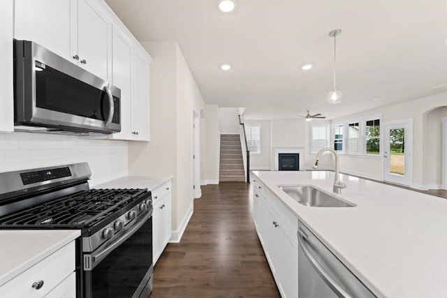 kitchen with stainless steel appliances, white cabinets, sink, hanging light fixtures, and dark wood-type flooring