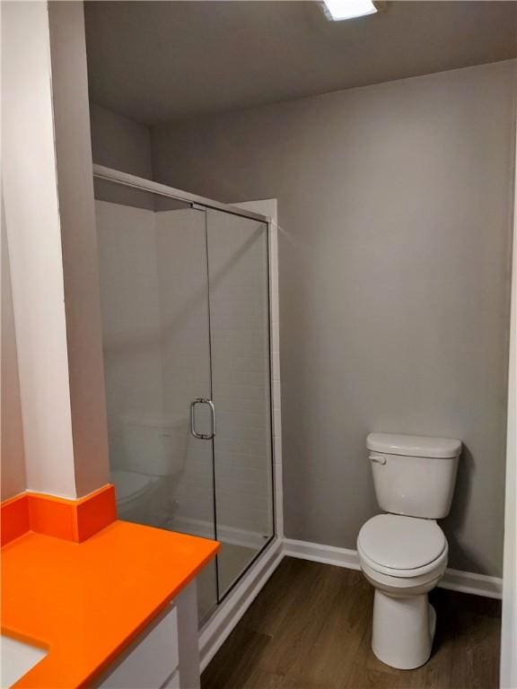 bathroom featuring hardwood / wood-style floors, an enclosed shower, and toilet