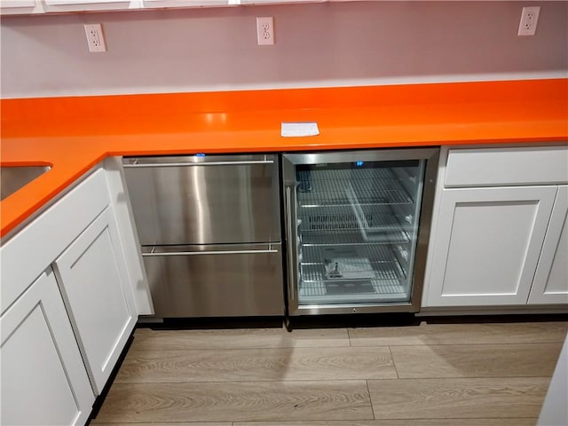 interior details featuring light hardwood / wood-style flooring, beverage cooler, and white cabinets