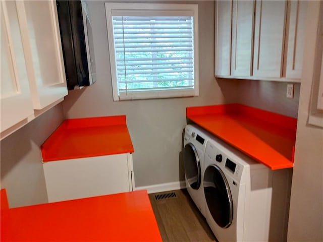 laundry area featuring hardwood / wood-style flooring, cabinets, and washing machine and clothes dryer