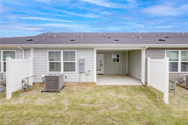 rear view of property with a lawn, a patio, and central AC