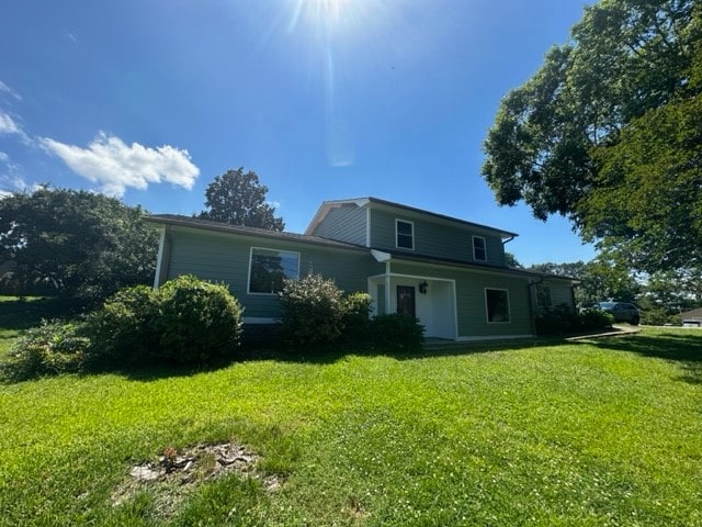 rear view of property featuring a lawn