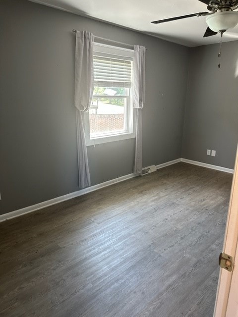 empty room with dark hardwood / wood-style flooring and ceiling fan