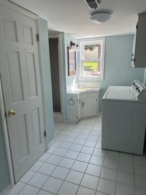 laundry room with separate washer and dryer, light tile patterned floors, and cabinets