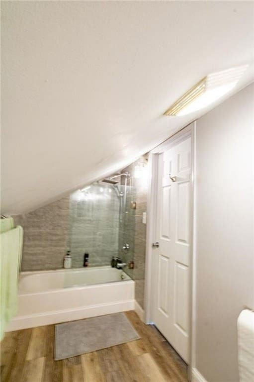 bathroom featuring lofted ceiling, tiled shower / bath combo, and hardwood / wood-style floors