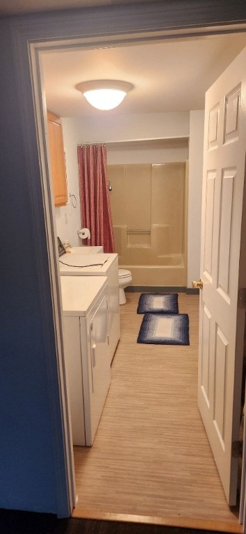 bathroom featuring hardwood / wood-style flooring, washer and dryer, vanity, and toilet