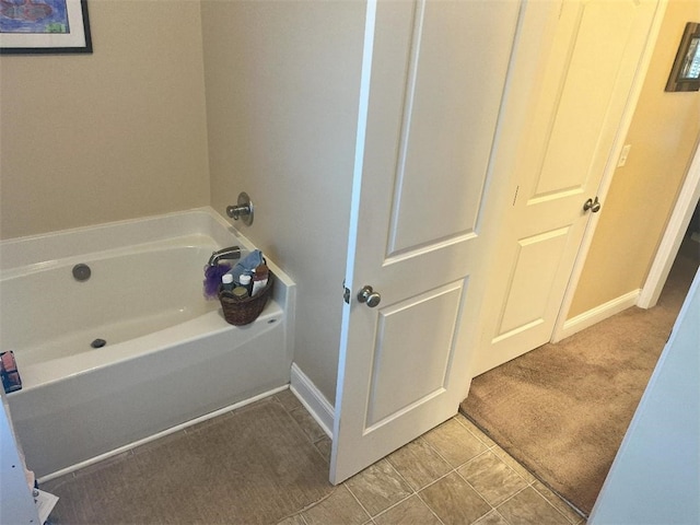bathroom with baseboards, tile patterned flooring, and a bath