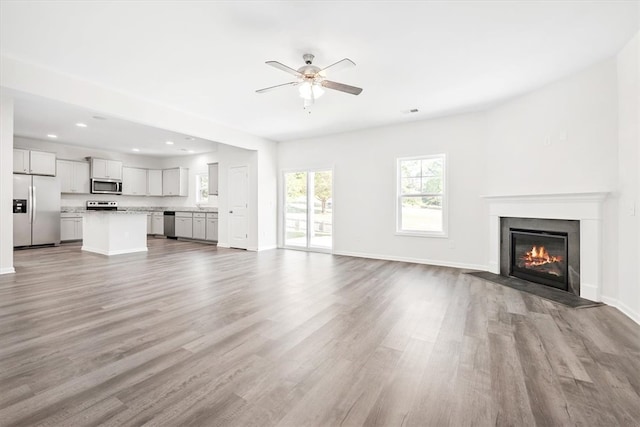 unfurnished living room with ceiling fan and light wood-type flooring