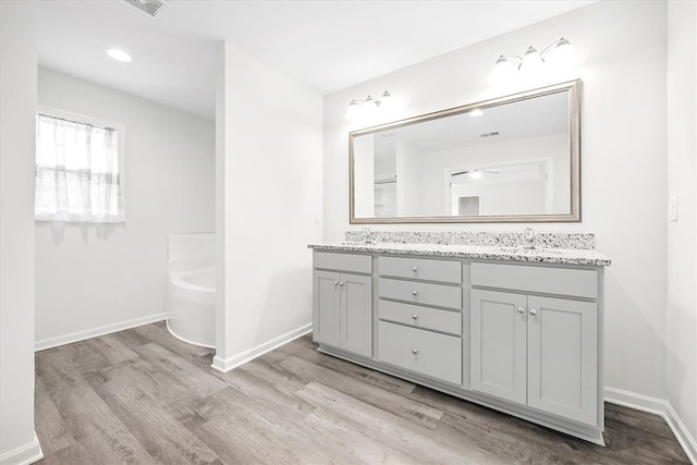 bathroom with a tub to relax in, vanity, and hardwood / wood-style floors