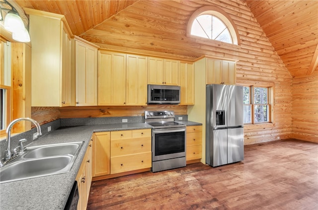 kitchen featuring lofted ceiling, hardwood / wood-style flooring, stainless steel appliances, sink, and rustic walls