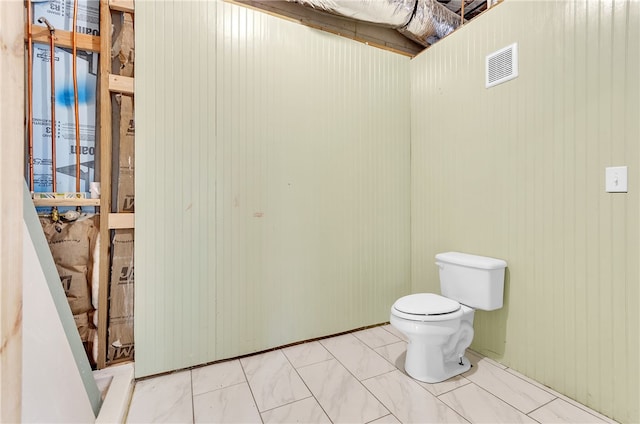 bathroom featuring toilet and wood walls