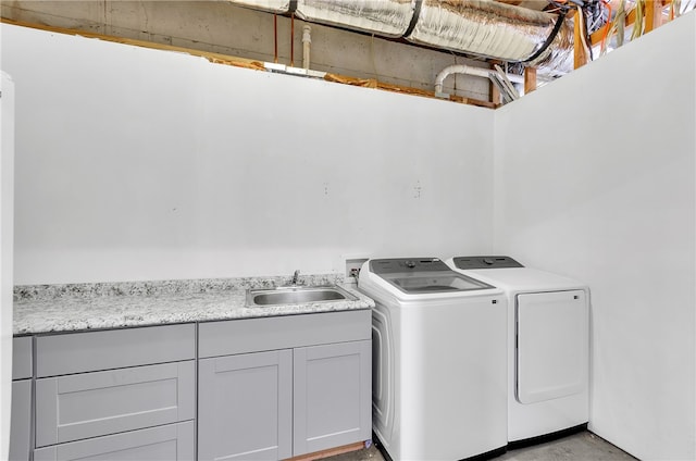 clothes washing area with cabinets, washer and dryer, and sink