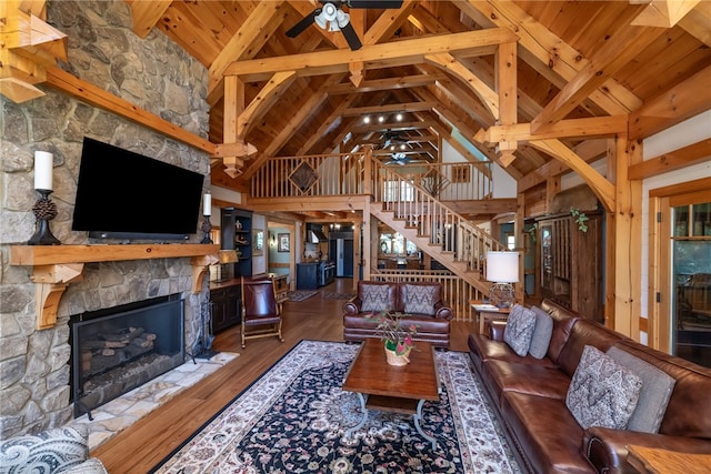 living room featuring beamed ceiling, hardwood / wood-style flooring, a fireplace, high vaulted ceiling, and wooden ceiling