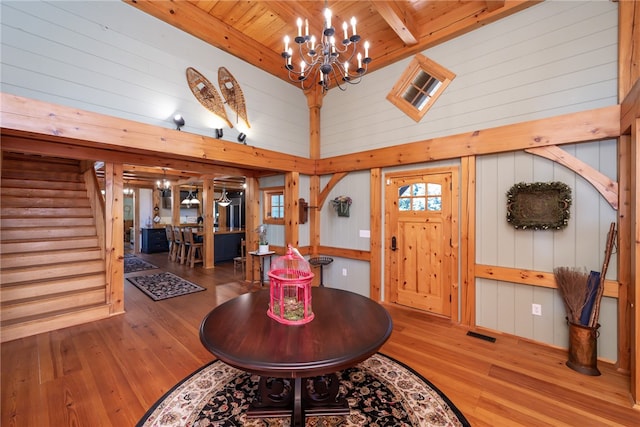 entrance foyer with high vaulted ceiling, wooden walls, a chandelier, and hardwood / wood-style flooring