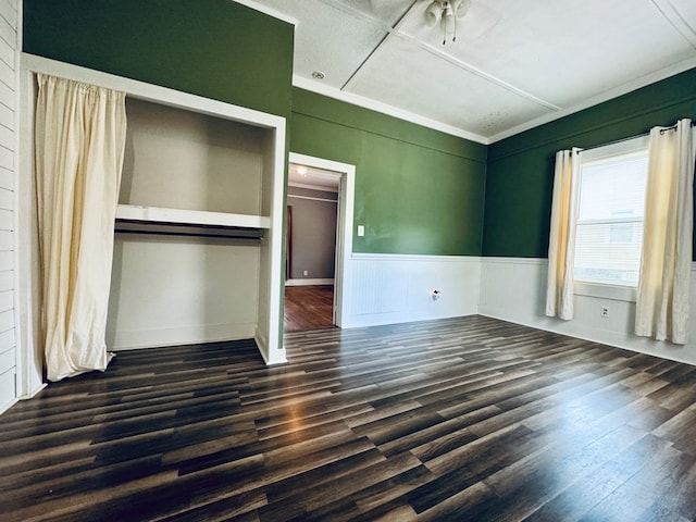 unfurnished bedroom with a closet, crown molding, and dark hardwood / wood-style flooring