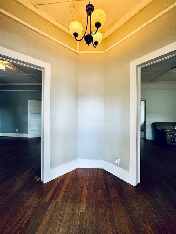 spare room with ceiling fan with notable chandelier and dark hardwood / wood-style floors