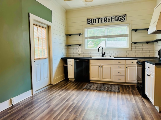 kitchen featuring decorative backsplash, dark wood-type flooring, wood walls, black appliances, and sink