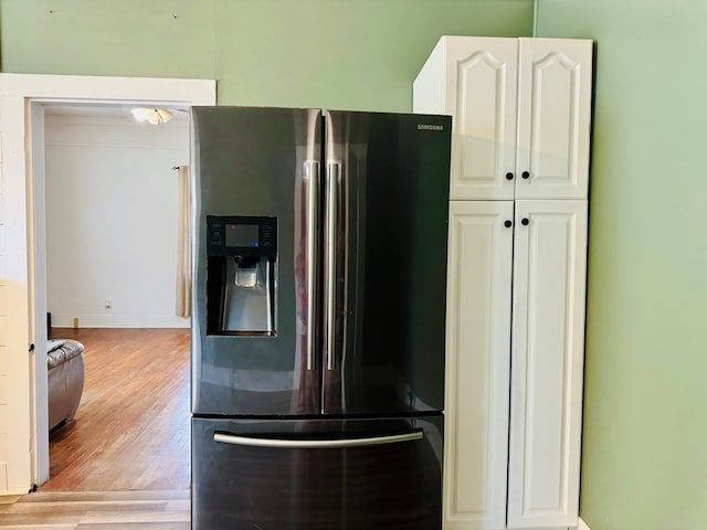 kitchen with light wood-type flooring, stainless steel refrigerator with ice dispenser, and white cabinets