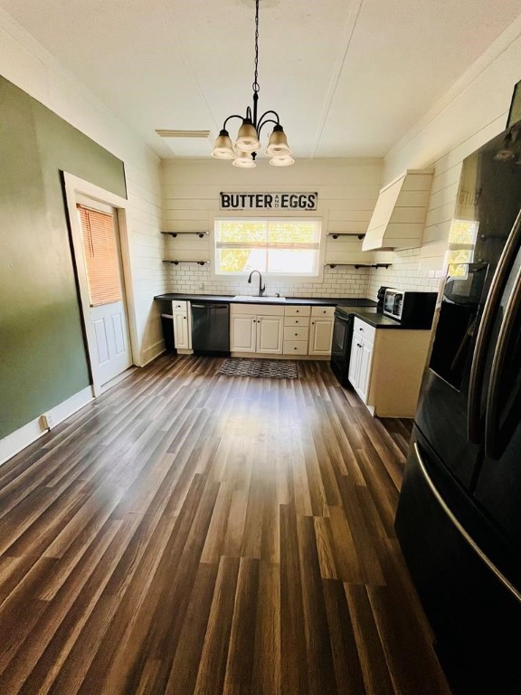 kitchen featuring black appliances, backsplash, dark hardwood / wood-style flooring, and pendant lighting