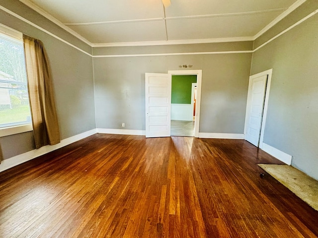 empty room with crown molding and dark hardwood / wood-style flooring