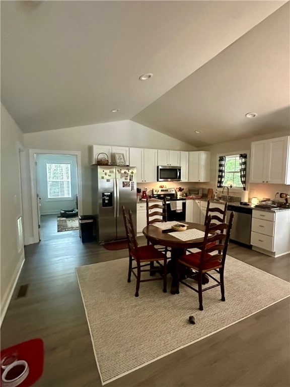 dining space featuring vaulted ceiling and dark wood-type flooring