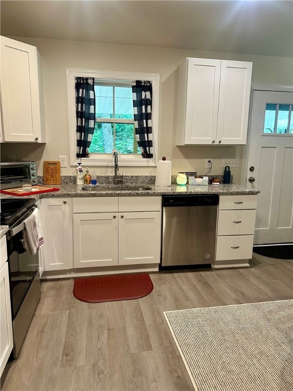 kitchen featuring light stone counters, appliances with stainless steel finishes, sink, and white cabinetry